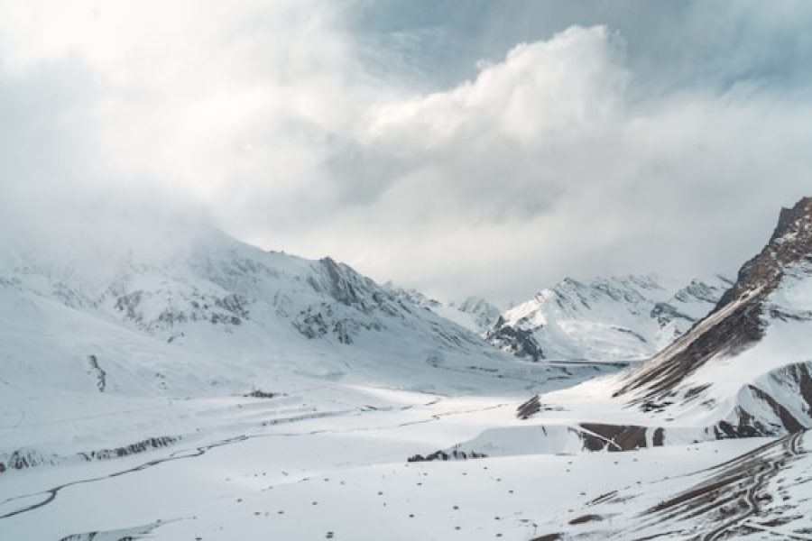 a snow covered mountain range under a cloudy sky